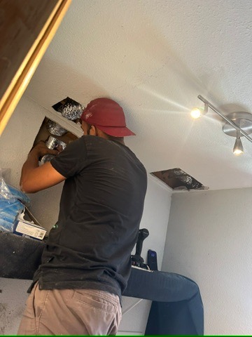 HVAC technician performing maintenance on ceiling unit